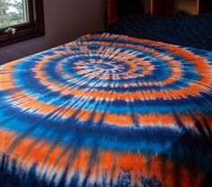 a bed with an orange and blue tie - dyed comforter