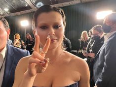 a woman making the v sign with her fingers in front of people at an event