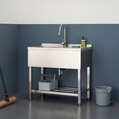 a white sink sitting on top of a metal stand next to a bucket and mop