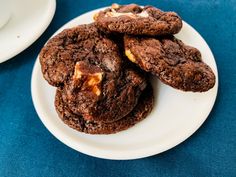 three chocolate cookies are stacked on top of each other in front of a cup and saucer