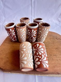 six brown and white vases sitting on top of a wooden board