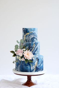 a three tiered blue and white cake with flowers on top