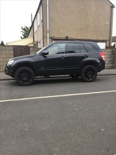 a black suv parked in front of a house