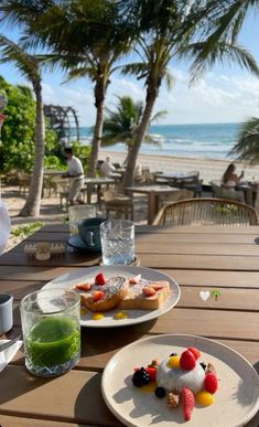 two white plates topped with desserts on top of a wooden table next to the ocean