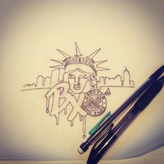 a drawing of the statue of liberty and two pens on top of a white surface