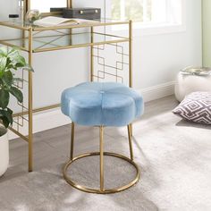 a green stool sits in front of a mirror on a gold stand next to a potted plant