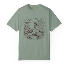 Step into a world of magic with our enchanting woodland fairy cotton tee. This soft, comfortable t-shirt features a whimsical fairy nestled in a lush, vibrant landscape. Perfect for those who love a touch of fantasy in their wardrobe, this tee is as versatile as it is charming. Whether you're heading out for an adventure or enjoying a cozy day at home, this shirt brings a bit of fairy tale wonder to your everyday life. Fairy Grunge Cotton T-shirt With Graphic Print, Nature-inspired Green Cotton T-shirt, Green Nature-inspired Cotton T-shirt, Green Cotton Nature-inspired T-shirt, Cotton Fairycore T-shirt For Summer, Summer Fairycore Cotton T-shirt, Summer Fairycore Crew Neck T-shirt, Cotton Fairycore T-shirt With Crew Neck, Cotton Fairycore Crew Neck T-shirt