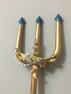 two gold candles with blue and white decorations on them are hanging from the wall together