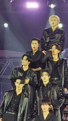 the group of young men are posing for a photo in front of a stage with lights