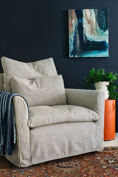 a living room with a striped chair and potted plant