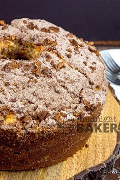 a cake with powdered sugar on top sitting on a wooden platter next to a fork