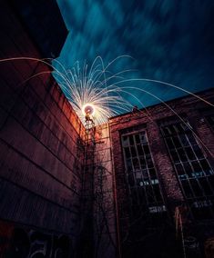 fireworks are lit up in the night sky above an old brick building with graffiti on it