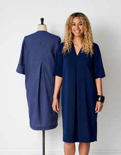 a woman standing next to a mannequin wearing a blue shirt dress with pockets