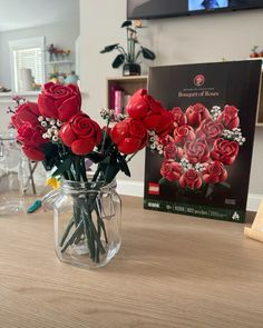 a vase filled with red roses sitting on top of a table next to a book