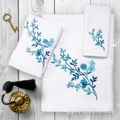 two white towels with blue flowers on them next to an antique brass door knob and key