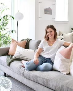 a woman sitting on top of a gray couch