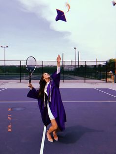 a woman in a graduation gown is on a tennis court with her racquet up