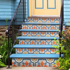 blue and yellow painted steps leading up to a door with an orange flowered design on it