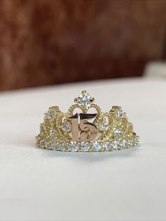 "This elegant ring is crafted from 14K tri-color gold and features cubic zirconia accents along with a stunning design. It bears the stamp \"14k\" on the inside, affirming its authenticity as solid gold." Gold Quinceanera Rings, Quince Rings 15 Gold, Quince Jewelry Gold, 15 Rings Quinceanera Gold, Quince Rings Gold, Xv Rings, 15 Rings Quinceanera, Quinceañera Rings, Quinceanera Rings