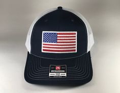 American Flag 6 Panel Adjustable Snapback Trucker Mesh Hat Richardson 112, US Flag Hat, American Flag Hat, Richardson 112 Embroidered American Flag Heat Sealed Patch Richardson 112 Hat Details:    -60/40 cotton/polyester    -100% polyester mesh back    -Structured, six-panel, mid-profile    -Pre-curved contrast stitched visor    -Underbill matches the color of the visor    -Adjustable plastic snapback Hat will be shipped in a box for protection. White Americana Hat With Adjustable Fit, White Adjustable Americana Hat, White Patriotic Baseball Cap With Flat Bill, White Patriotic Flat Bill Baseball Cap, White Patriotic Hat With Curved Brim, Patriotic White Flat Bill Hat, Patriotic Flat Bill Sports Hat, White Patriotic Snapback Hat With Flat Bill, Patriotic Snapback Sports Hat