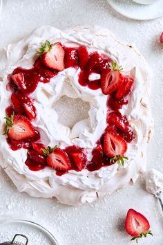 a cake covered in whipped cream and strawberries on top of a white tablecloth