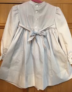 "Grey with long sleeves. Smocked bodice & a lace collar. Elasticsized wrists/2 top back buttons/smoke free environment/only issue(as seen in last picture)A green dot possibly marker on front/no size label/ true vintage. please pay attention to measurements/pit to pit 12\"blouson/waist 11 1/2\"can be tied back with bow sashes/pit to wrist 11\"/length (shoulder to bottom 22\" w/an extra 3\" hem available (65)" Long Sleeve Dress With Smocked Back For Daywear, Long Sleeve Dress With Smocked Bodice For Daywear, Long Sleeve Cotton Smocked Dress For Spring, Long Sleeve Smock Prairie Dress For Spring, Long Sleeve Peasant Dress With Smocked Cuffs For Daywear, Cute Long Sleeve Smocked Dress For Spring, Cute Long Sleeve Fitted Smocked Dress, Cute Daywear Dresses With Smocked Cuffs, Long Sleeve Smock Prairie Dress For Daywear