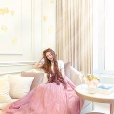 a woman in a pink dress sitting on a couch