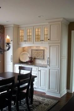 a dining room table and chairs in front of a wall mounted cabinet with glass doors