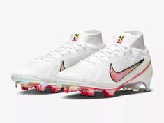 a pair of white and pink nike cleats on a white background with red accents