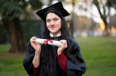 a woman in graduation gown holding a diploma