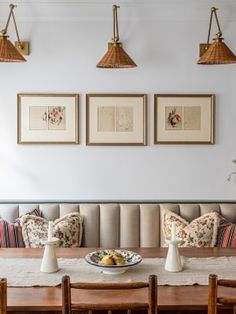 a dining room table with place settings and pictures on the wall in front of it