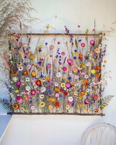 an arrangement of wildflowers is displayed on a wall