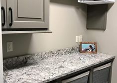 an empty bathroom with gray cabinets and marble counter tops in front of a white sink