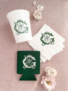 three paper napkins with monogrammed designs on them next to flowers and a coffee cup