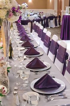 the table is set with purple linens and silverware for an elegant wedding reception