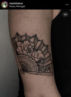 a woman's arm with a fan tattoo on it