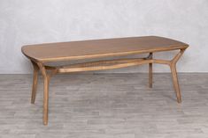 a wooden table sitting on top of a hard wood floor next to a white wall