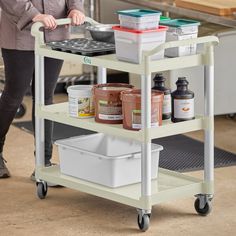 a woman standing next to a purple utility cart filled with food and condiments