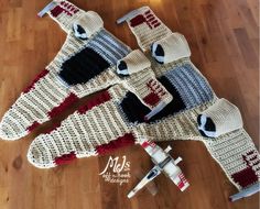 knitted sweaters and mittens laid out on the floor next to a toy airplane