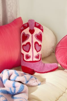 a bed with pink and red pillows, heart shaped mitts and blankets on it