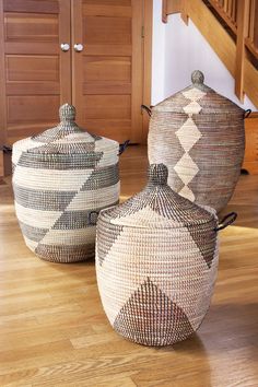 two baskets sitting on top of a wooden floor next to each other in front of a stair case