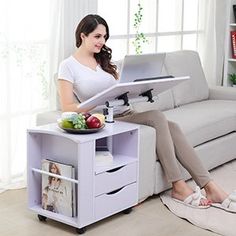 a woman sitting on a couch using a laptop computer while holding a tray with food