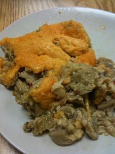 a white plate topped with meat and veggies covered in gravy on top of a wooden table