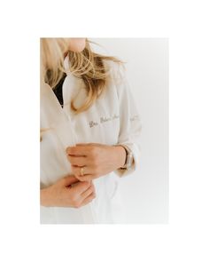 a woman wearing a white shirt and gold bracelet holding onto her wrist with both hands