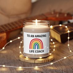 a lit candle sitting on top of a wooden table next to a string of lights