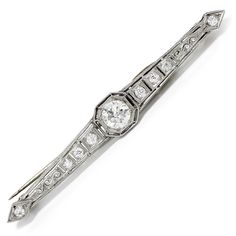 Description: The Art Deco period was known for its use of geometric shapes combined with elegant filigree forms, milgrain beaded edges, platinum and exquisite diamond’s. This brooch embodies all of these qualities. The 1920s bar pin exhibits at its center a vibrant round brilliant cut natural diamond weighing approximately 1.00 carat with a color grade of I and clarity grade of I2 as this diamond was added at a later date. It is bead set and surrounded by an octagonal geometric shape with milgra Classic Diamond White Diamond Brooch, Classic Platinum Brooch With Brilliant Cut, Classic Platinum Brooches With Diamond Accents, Classic Diamond White Brooch For Anniversary, Classic White Diamond Brooches, Classic Platinum Brooches, Classic Diamond Brilliant Cut Brooch, Classic Diamond Brooch With Brilliant Cut, Classic White Gold Diamond Brooch