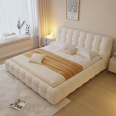 a white bed sitting in a bedroom on top of a hard wood floor next to a window