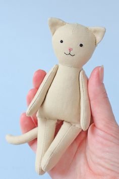 a hand holding a small stuffed cat in it's palm