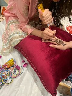 a woman sitting on top of a bed holding onto a pillow with henna tattoos on it