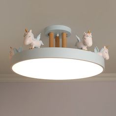 three unicorn figurines sitting on top of a circular light fixture in a children's room